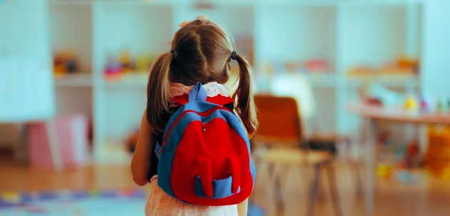 Criança com mochila e material escolar no regresso às aulas
